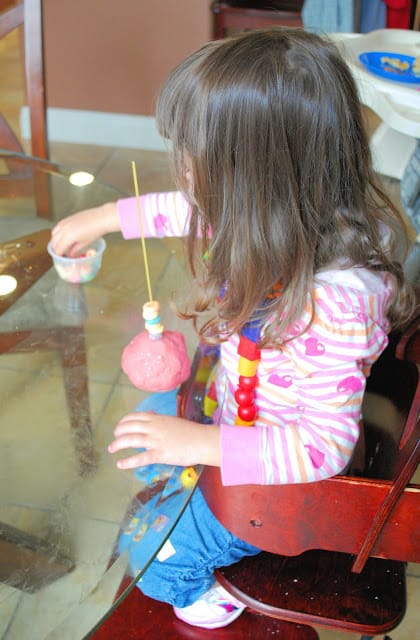 child stringing fruit loops on pasta