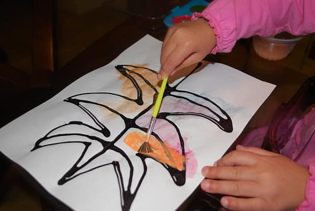 child painting leaf on paper