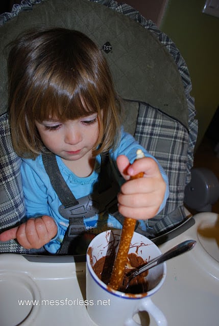child dipping pretzel in chocolate