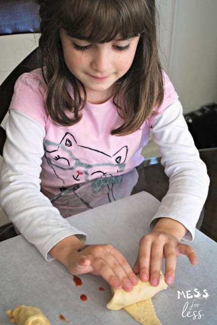 child rolling up pepperoni pizza crescents