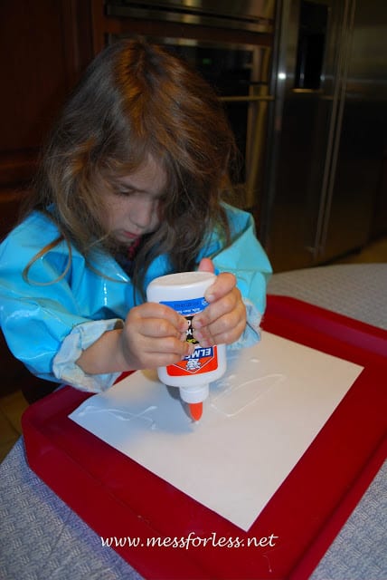 child squeezing glue on paper