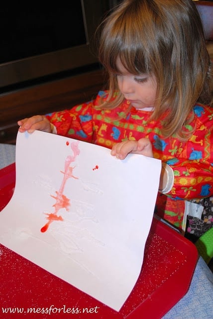 child holding paper with paint