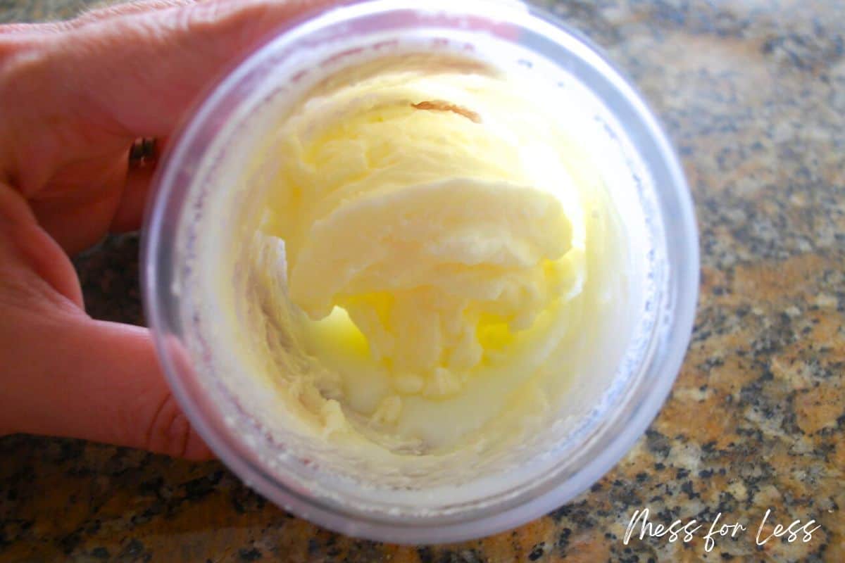 hand holding homemade butter in a small container