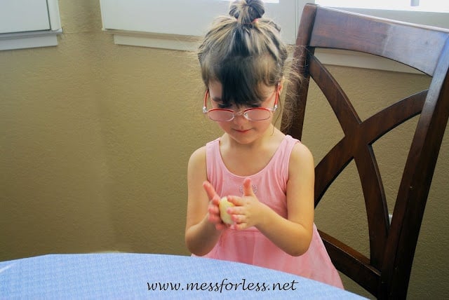 child rolling dough balls