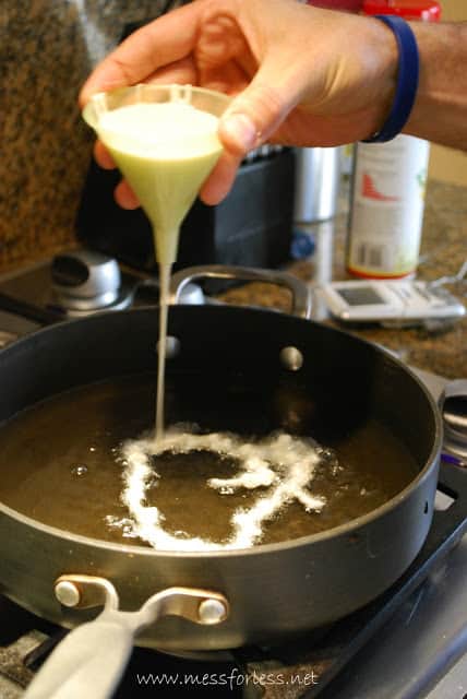 pouring funnel cake batter in oil