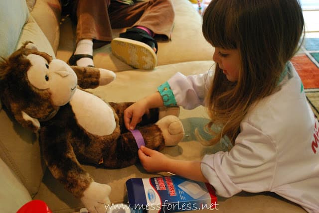 child placing band aid on stuffed animal