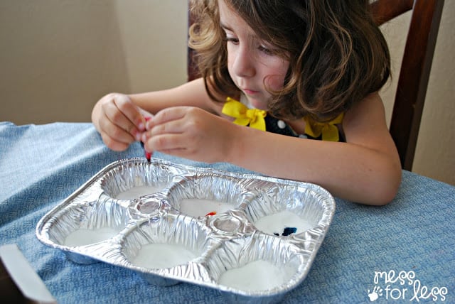 child adding food coloring to baking soda