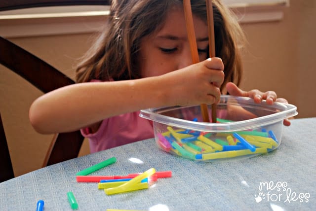 child picking up straws with tongs