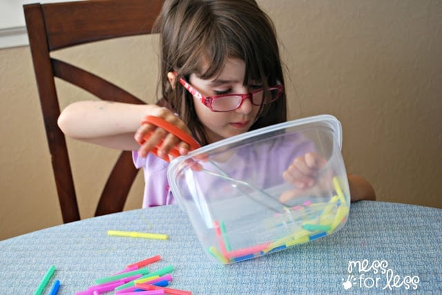 child picking up straws with tongs