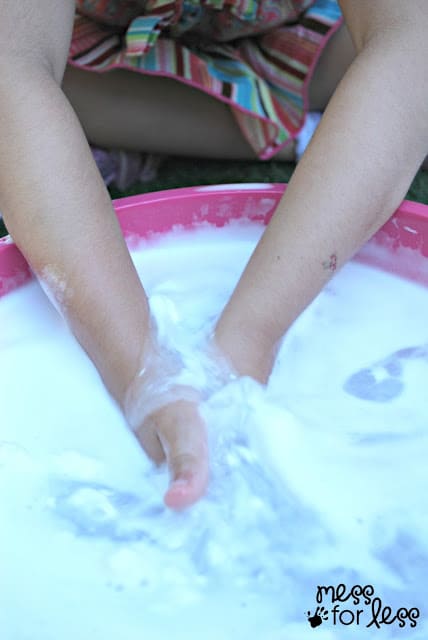 child with hands in bowl of shaving cream and water