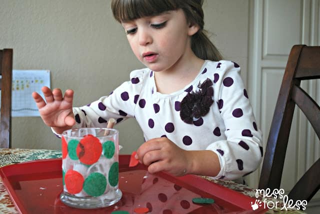 child gluing tissue paper on candle holder