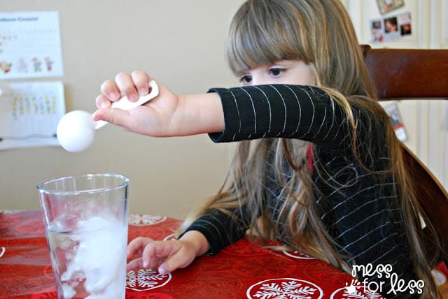 child pouring baking soda in a cup