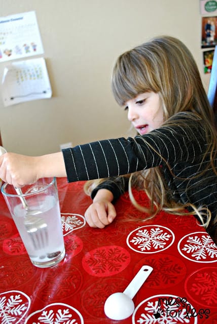 child stirring liquid in a glass