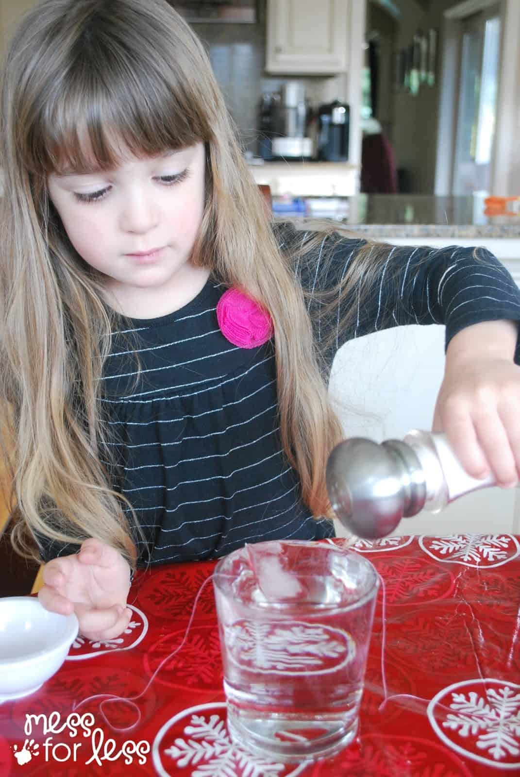 child pouring salt on thread and ice