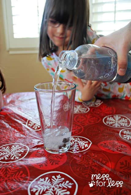 pouring seltzer into a glass with raisins