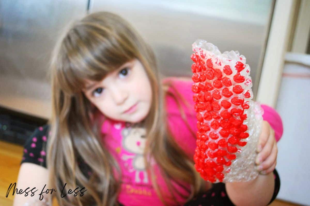 child holding up bubble wrap boot