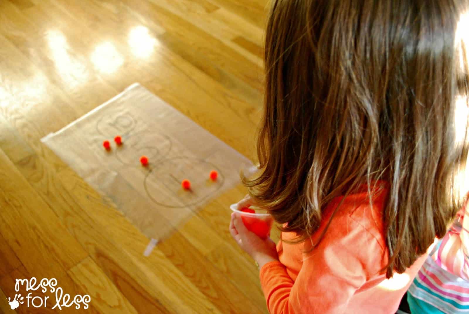 playing math game with contact paper and pom poms