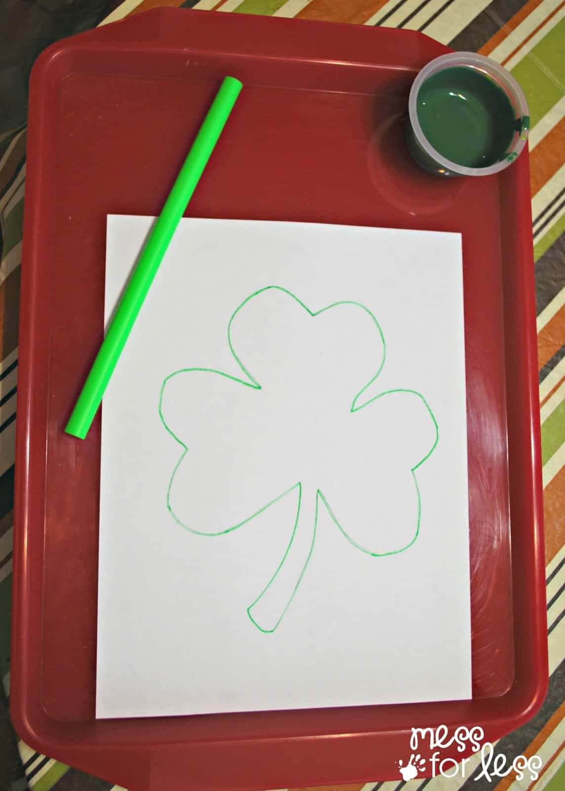 shamrock drawn on white paper on tray with paint and straw