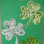 Three straw-painted shamrocks in varying shades of green adorn a green background, featuring the text St. Patricks Day Straw Painted Shamrocks. This delightful St. Patricks Day activity with straws is sure to bring festive cheer to your celebrations!.