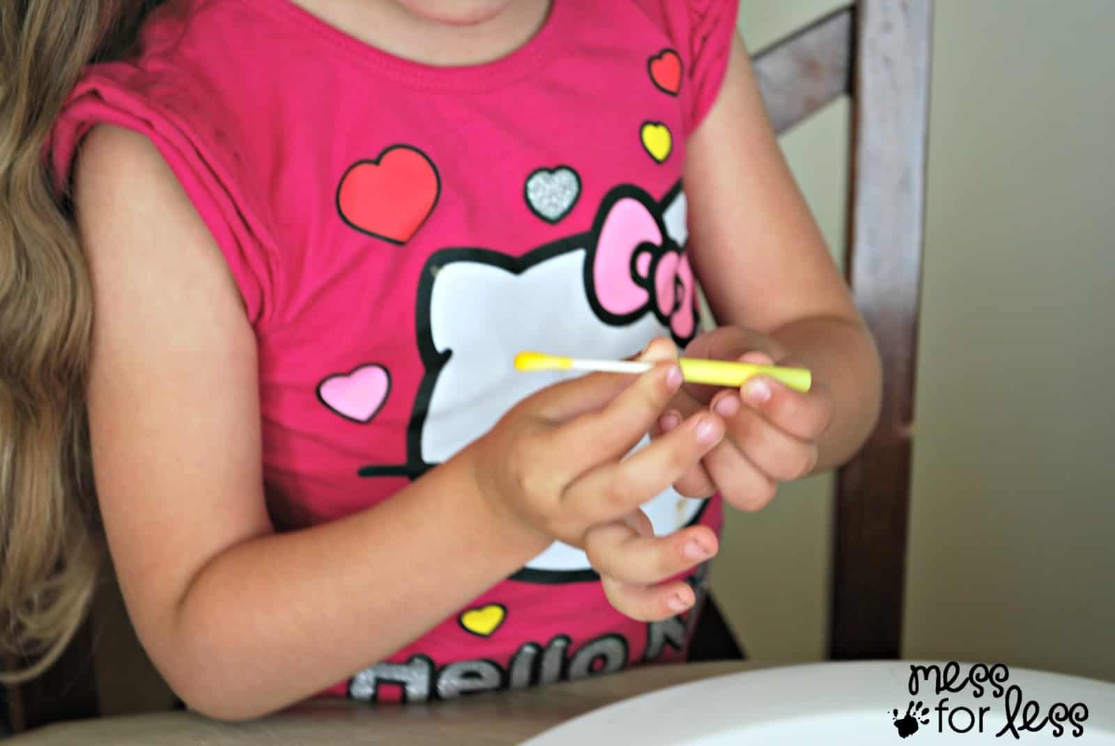 child putting a q-tip in a  straw