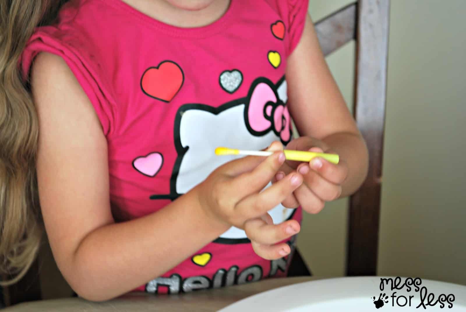 child putting a q-tip in a straw