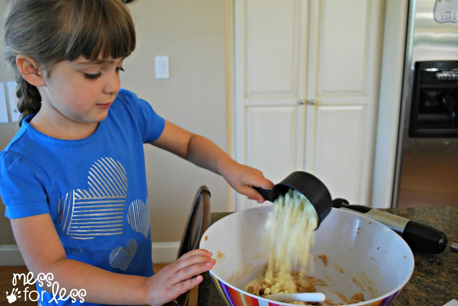 child adding white chocolate chips to bowl