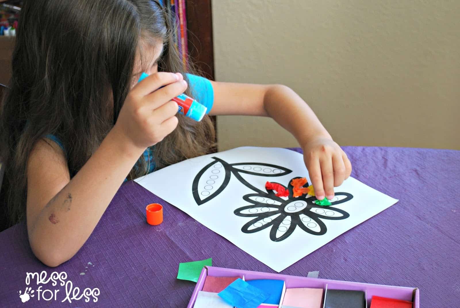 child gluing tissue paper on paper flower