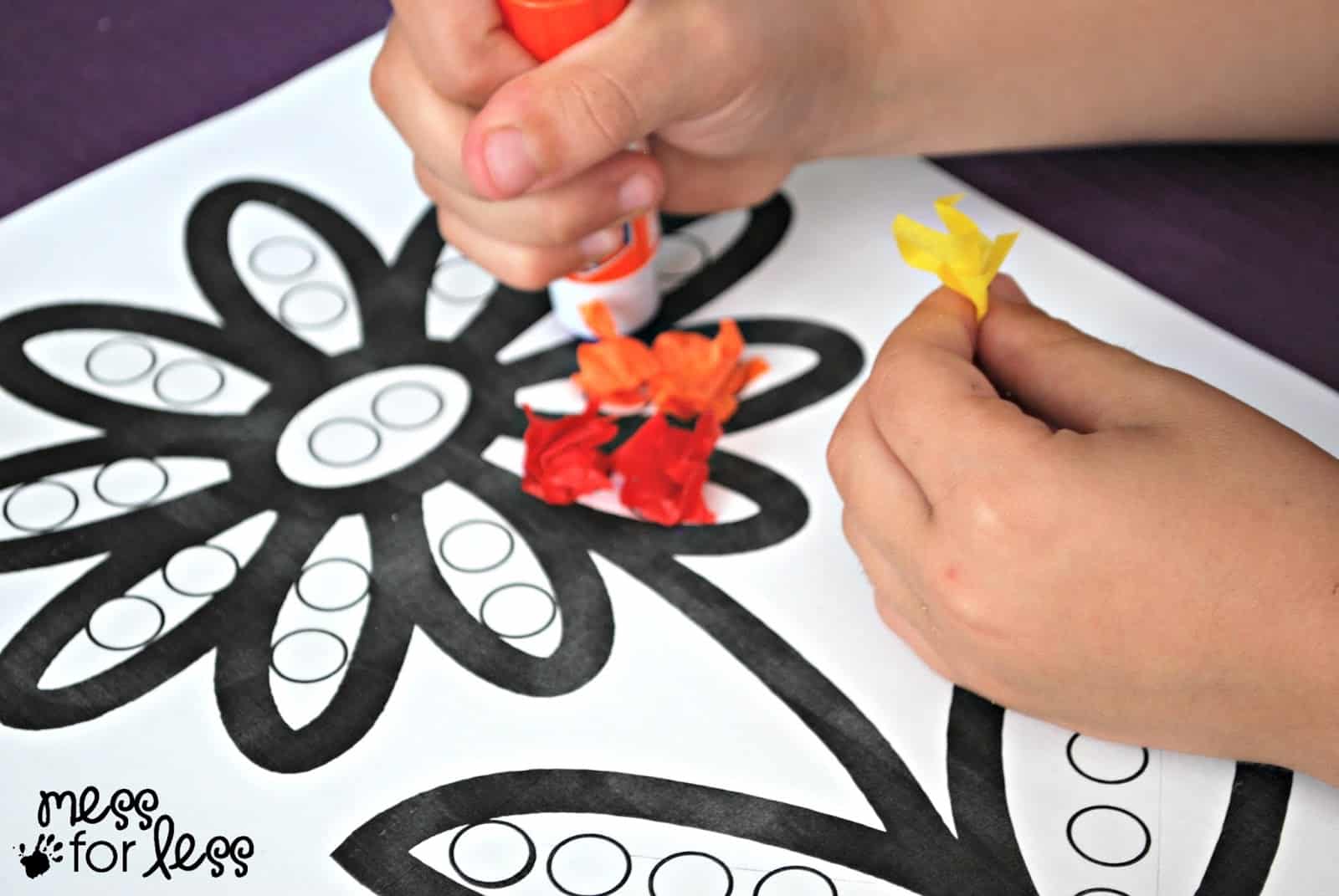 child gluing tissue paper on paper flower