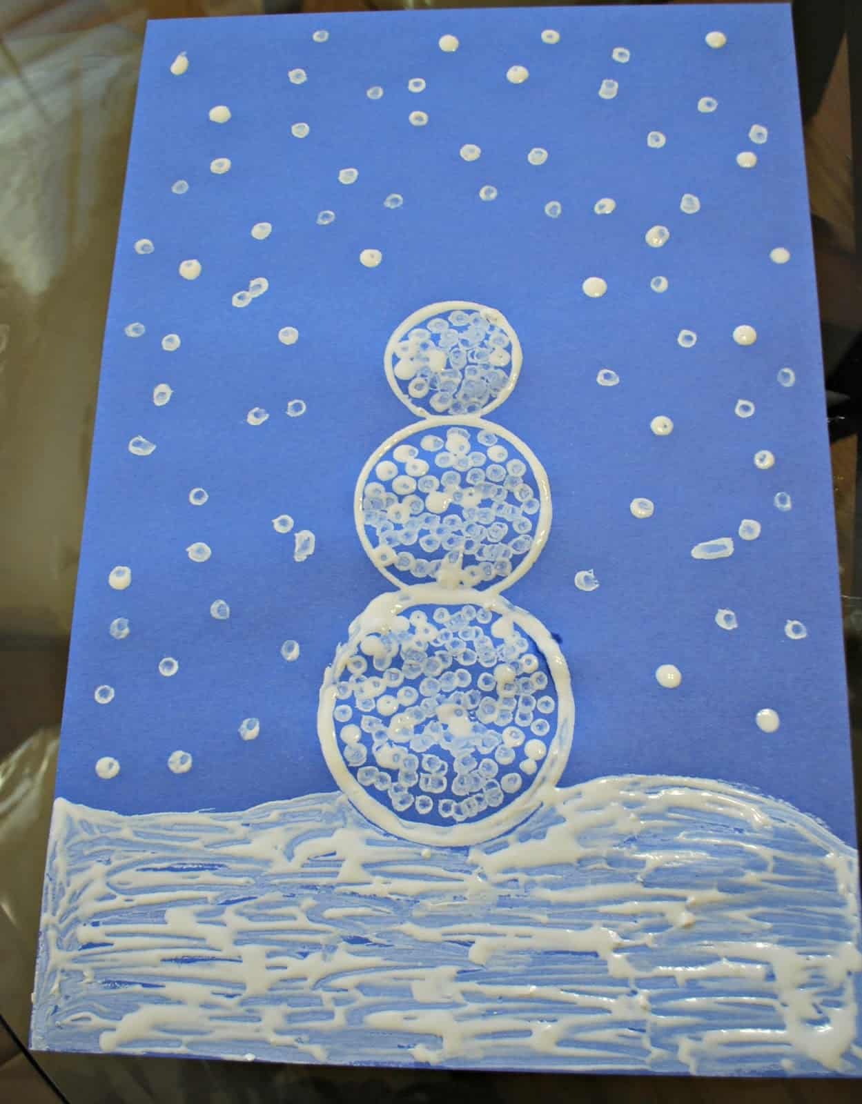 Painting a snowman on blue paper