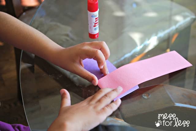 child folding pink and purple paper