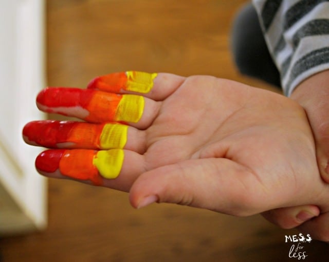 child's hand with fingers painted red, orange and yellow
