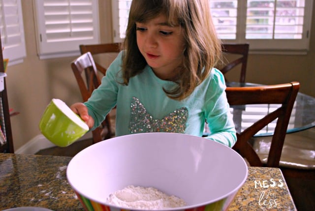 Child pouring flour into a bowl