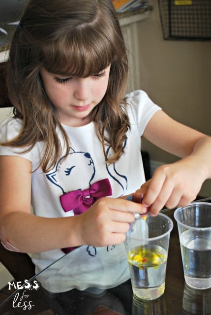 child putting food coloring in a cup
