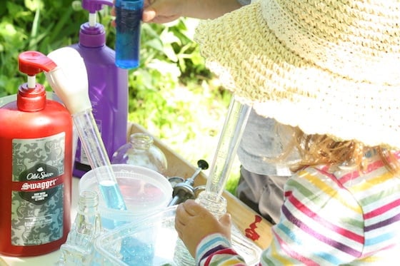 Child-using-turkey-baster-to-transer-water-into-glass-bottle