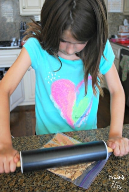 child crushing cracker crumbs with rolling pin
