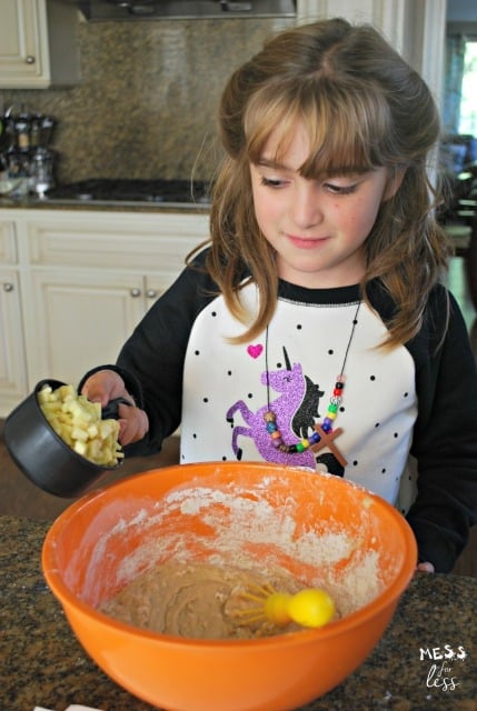 child placing cut apples in bowl