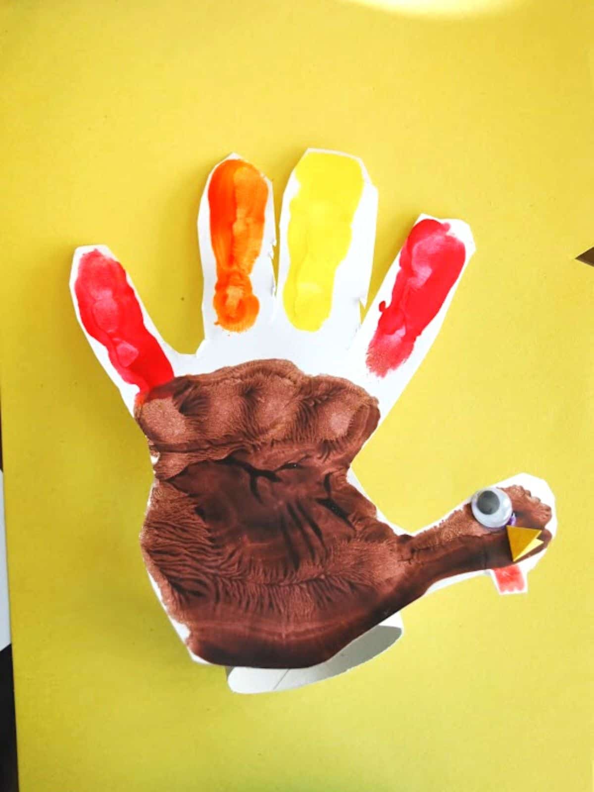 turkey handprint place card on yellow background.