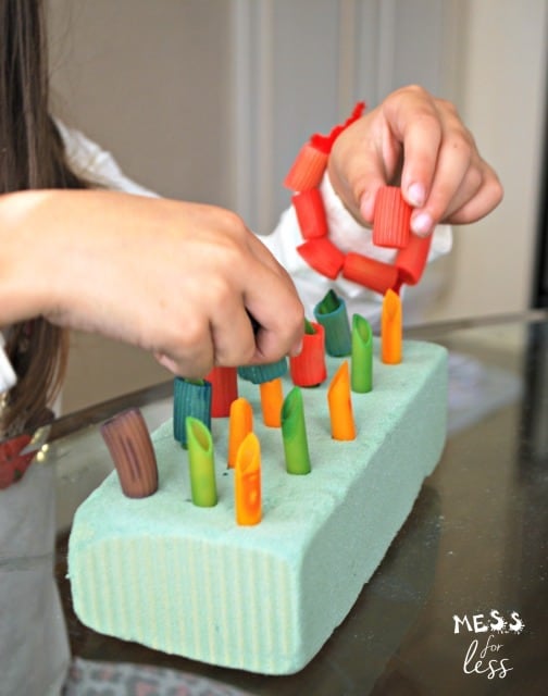 child playing with dyed pasta