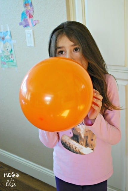 child blowing up balloon