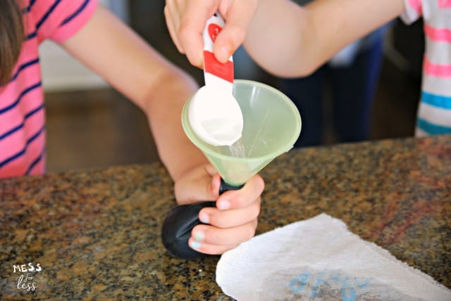 pouring vinegar into a balloon with a funnel