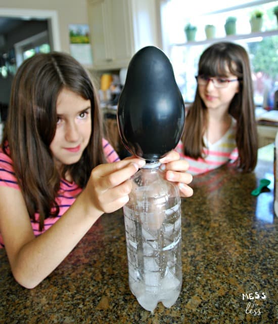child holding black balloon on bottle