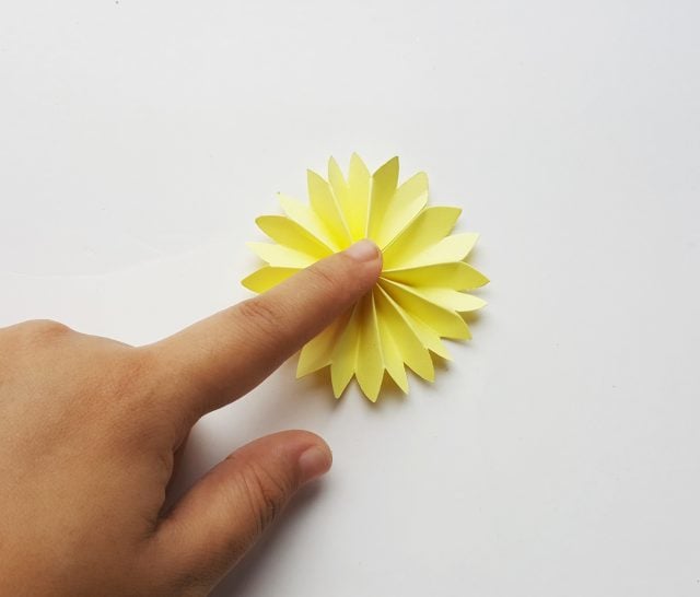 finger holding a paper flower