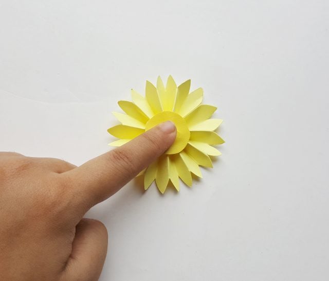finger holding a paper flower craft