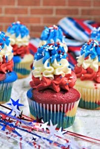 A table of Memorial Day desserts featuring a flag cake, red, white, and blue fruit parfaits, and star-shaped cookies.