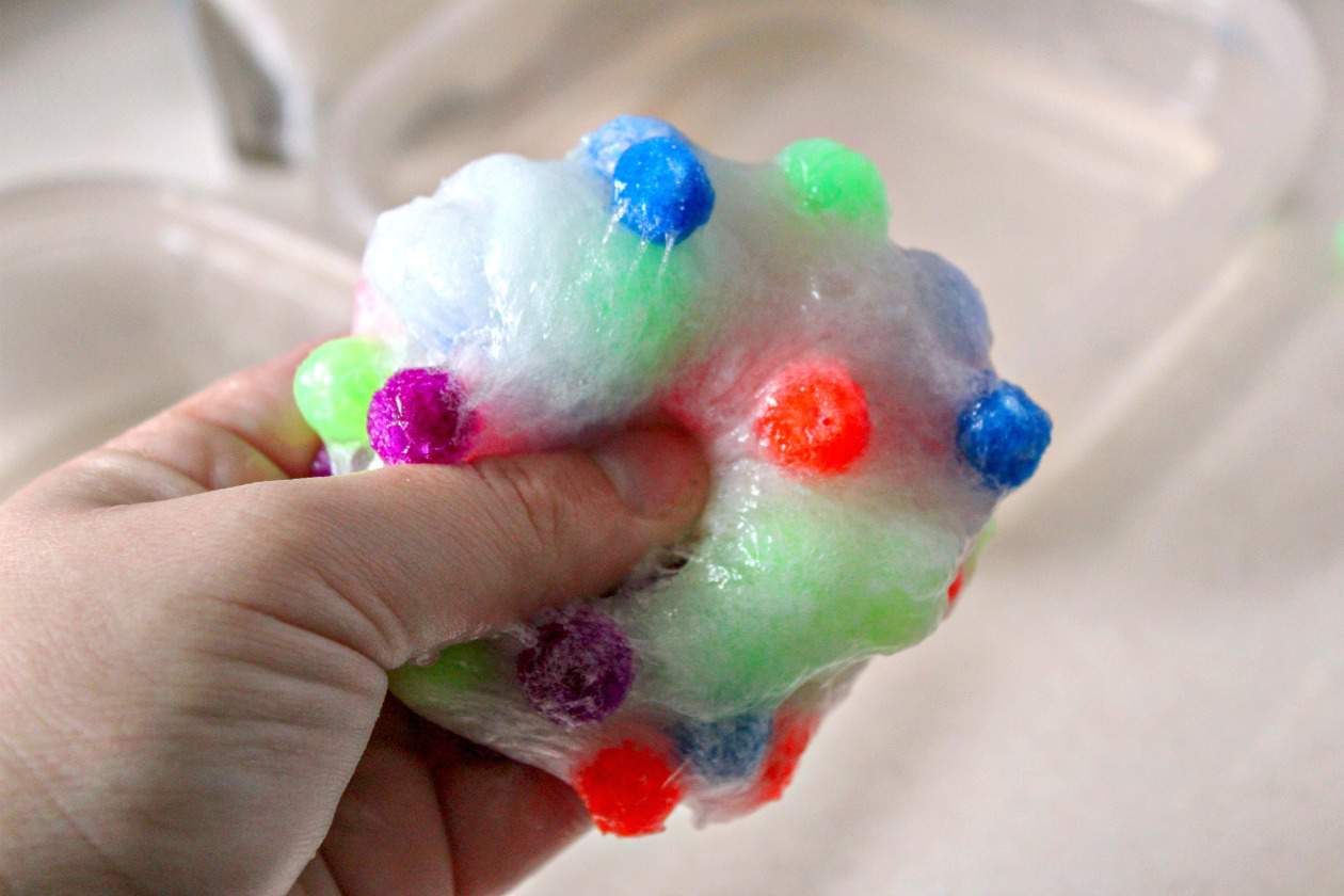 hand squeezing pom pom slime