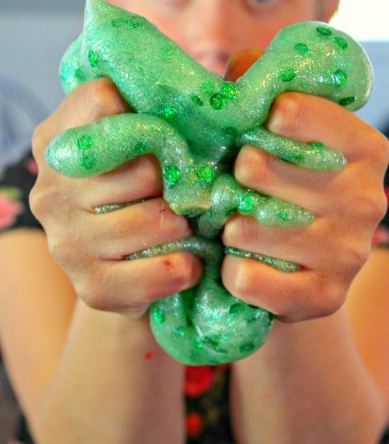 child squeezing green slime