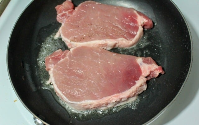 pork chops cooking in a skillet