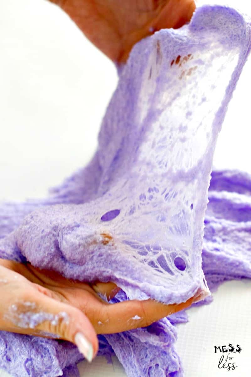 hands stretching purple slime made with instant snow