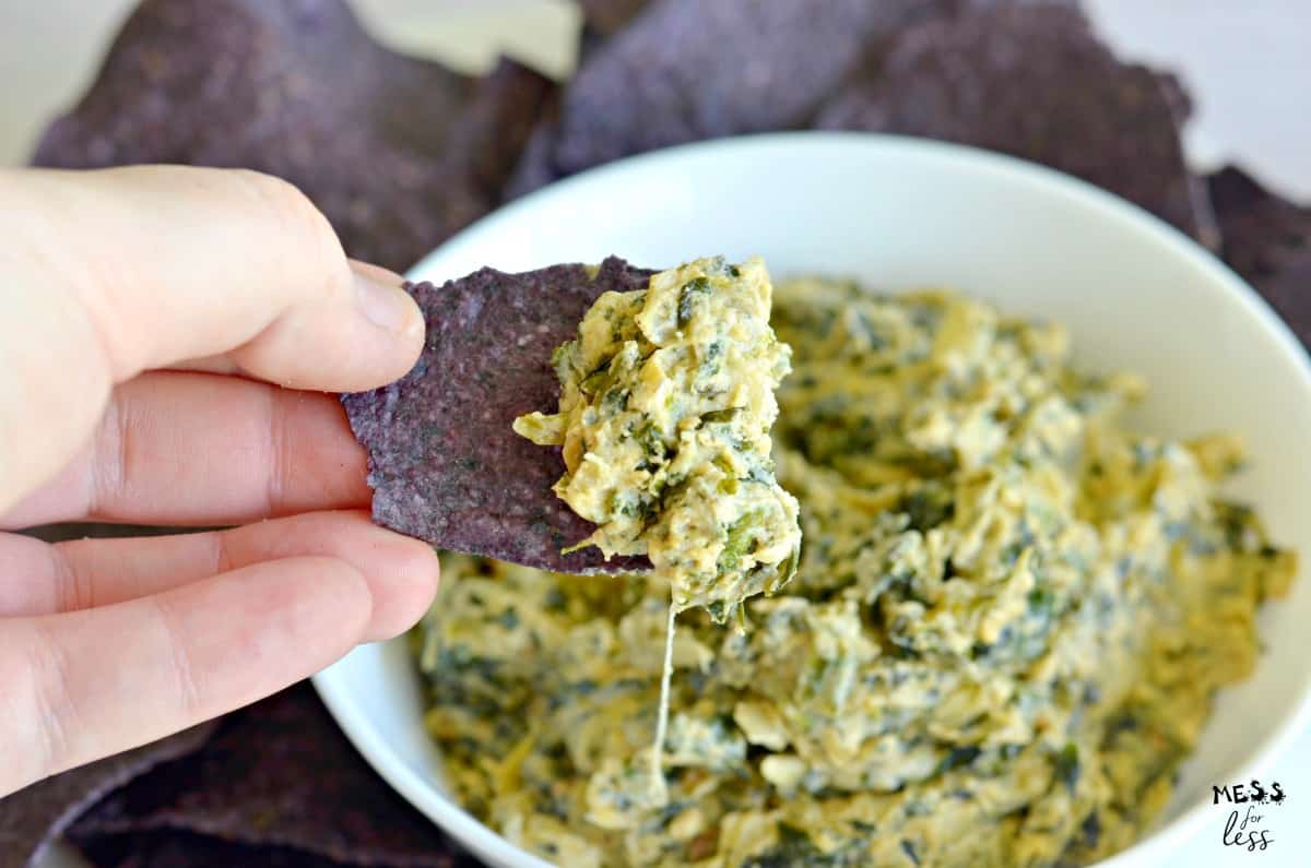 spinach artichoke dip on chip being held by hand