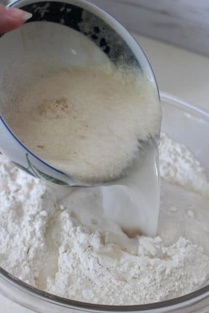 pouring yeast water into a bowl of flour